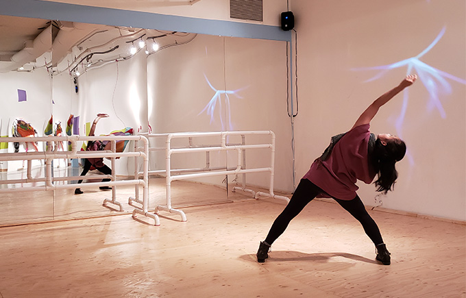 A dancer in movement in a dance studio space